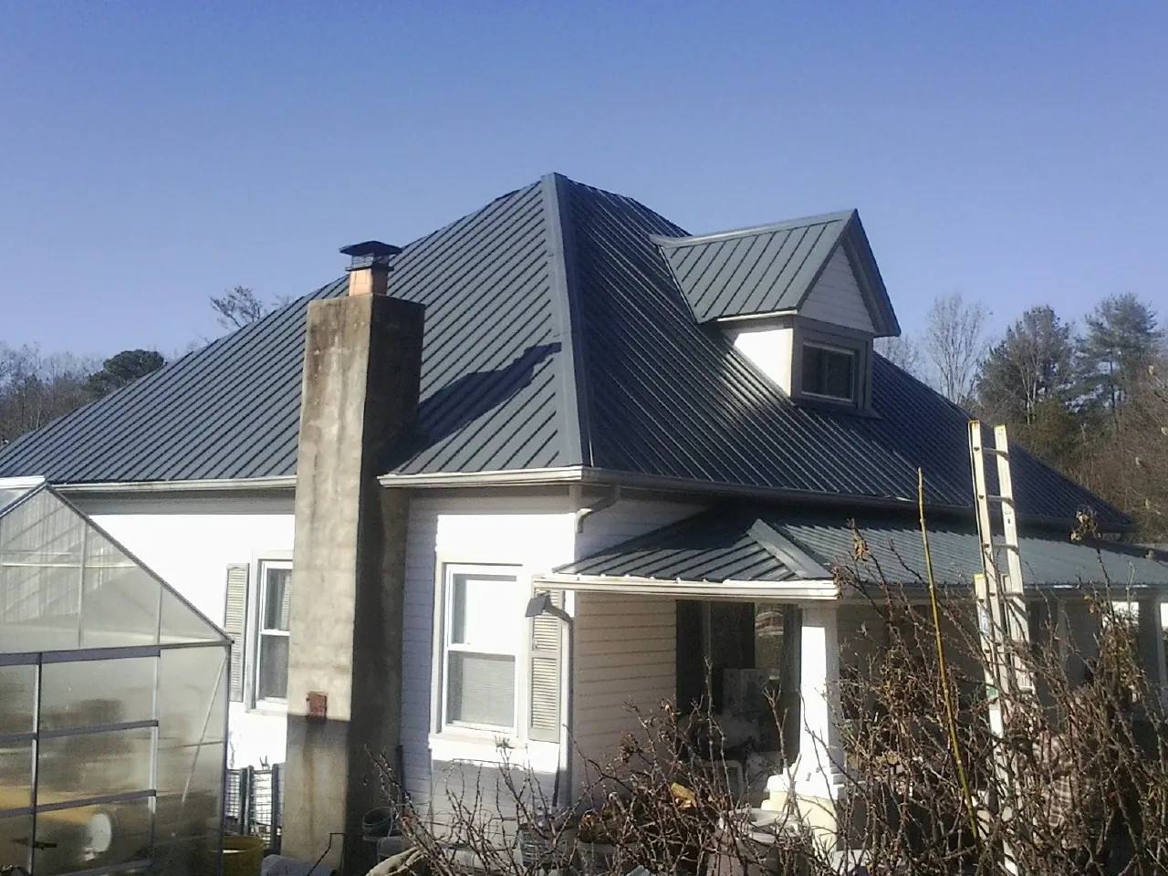 Dark blue standing seam metal roof on a white farmhouse with dormer — Slate & Tile Roof Repair by Roofing Brothers in Spring Church