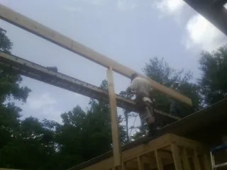 Carpenter setting a ridge beam over a new addition frame — Ice Dam Removal by Roofing Brothers in Spring Church