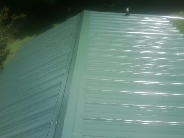 New green metal panels meeting at the ridge of a roof — Flat Roof Repair work by our crew in Spring Church