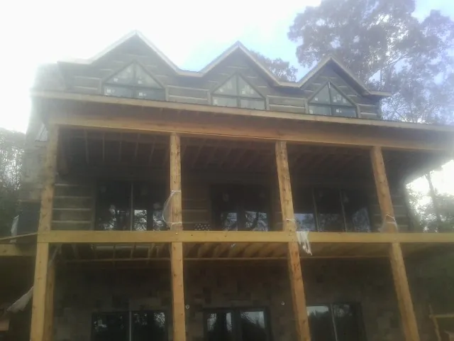 Dormers and porch framing on a large log home under construction — Roof Coating work by our crew in Spring Church