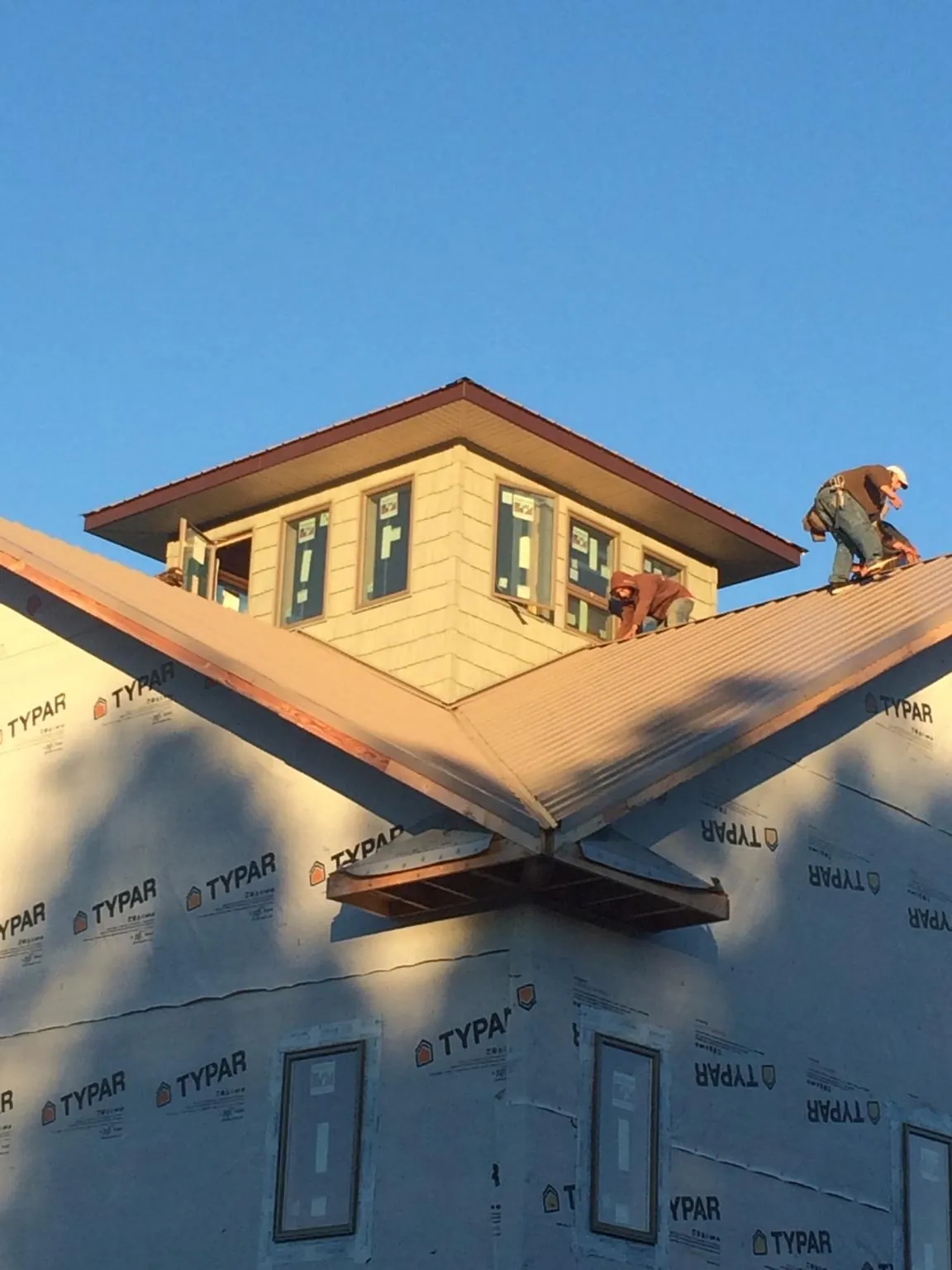 Roofers working around a rooftop cupola on a new metal roof at sunset — Roof Waterproofing in Spring Church by Roofing Brothers